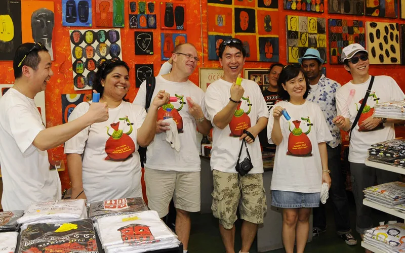 ABB participants in matching printed T-shirts laughing together in a colourful craft shop
