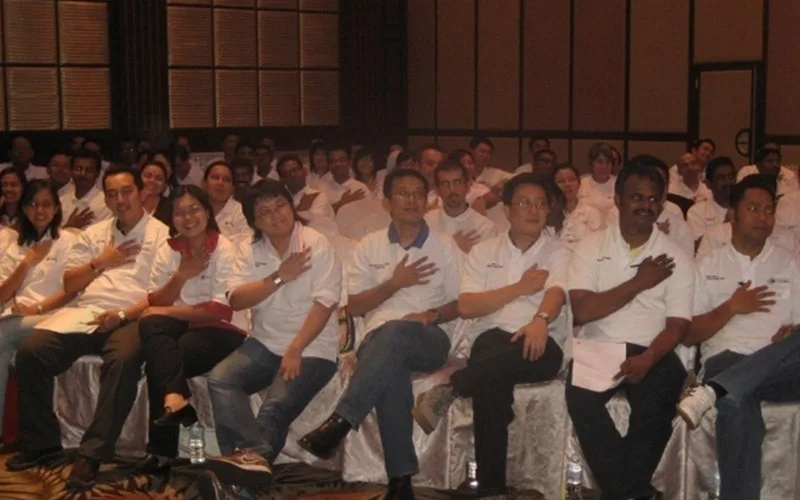 Carrefour staff seated in a ballroom with their hands on their hearts