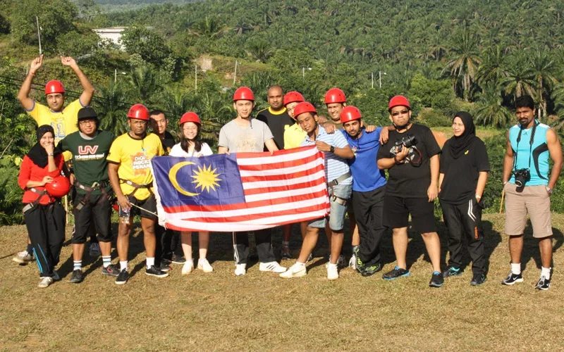 DiGi staff holding a Malaysian flag outdoors
