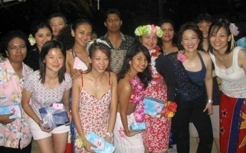 FJ Benjamin staff in floral outfits and leis holding wrapped prizes at an evening event