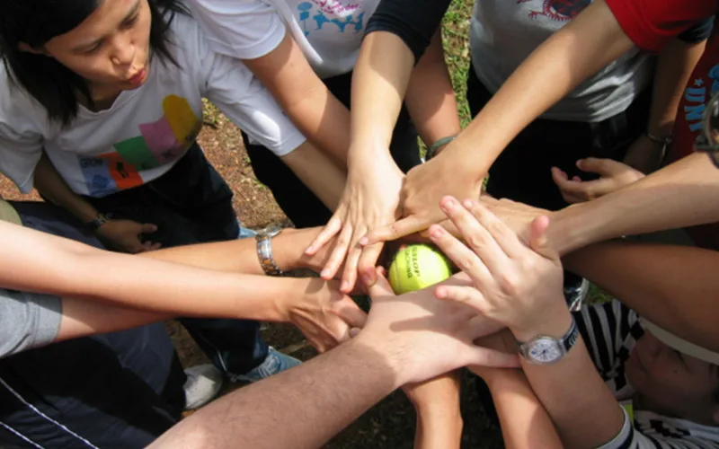 Many hands joined together over a ball