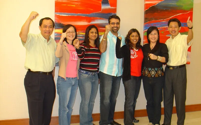 Seven MYOB staff raising their fists in front of abstract paintings