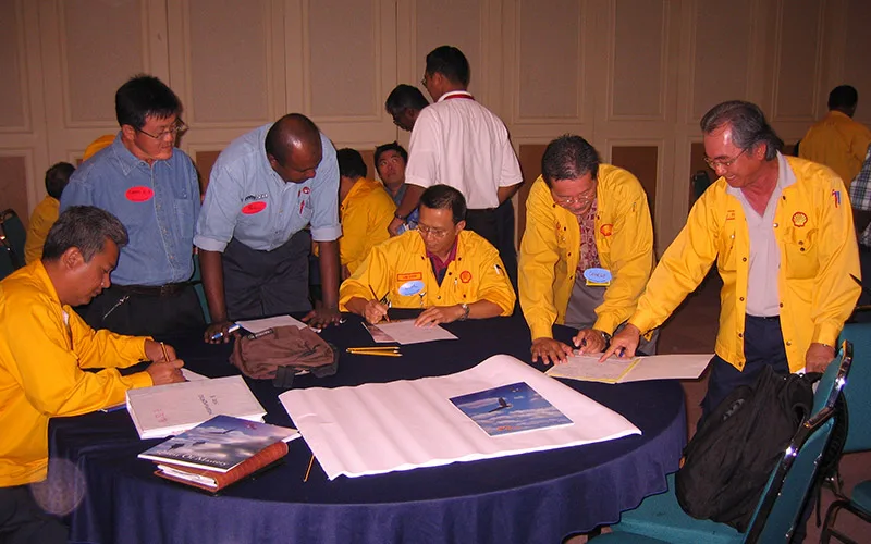 Participants working around a table at a QOM alignment session