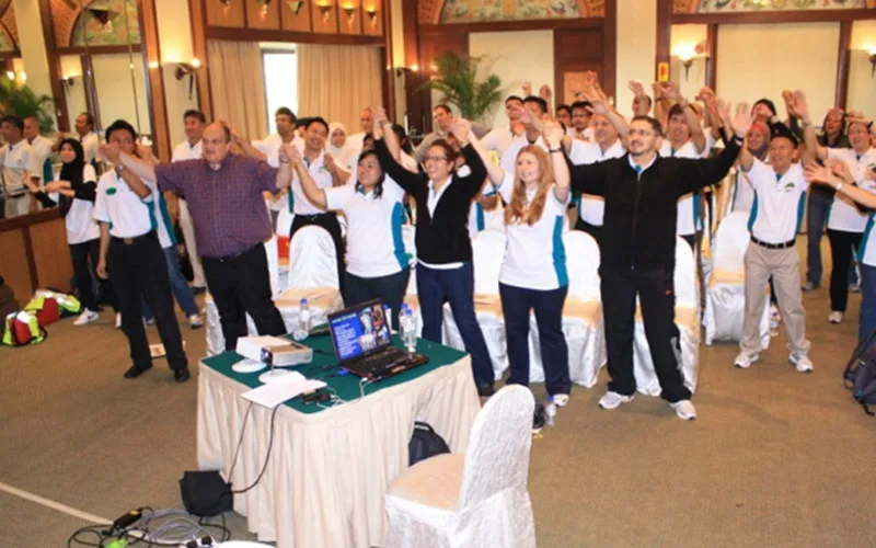Participants in a hotel ballroom stretching their arms overhead during an energiser