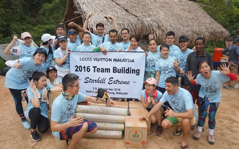 Louis Vuitton Malaysia team cheering behind their 2016 Team Building Starhill Extreme banner at a jungle camp